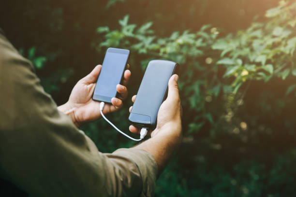 tourist mit smartphone und ladegerät geht im sommerwald spazieren guy mit powerbank geht in der natur verloren. moderne technologien sollen immer online und in kontakt bleiben. - recharger stock-fotos und bilder