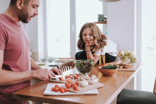 istock Cute little girl watching how father cooking dinner 1132991028