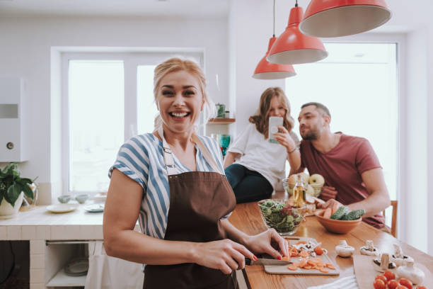 istock Charming lady cooking dinner while her husband and daughter using cellphone 1132991044