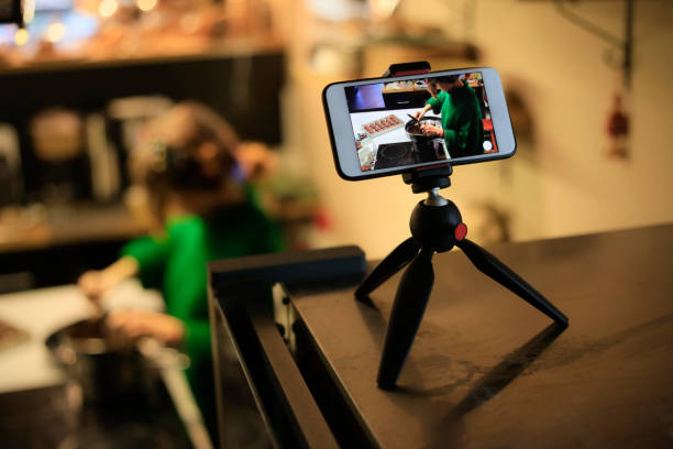 istock Woman in kitchen recording video on mobile phone 1132992304