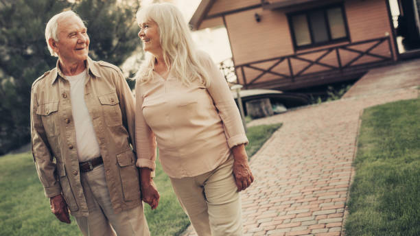 istock Cheerful smiling grey haired twosome fronting house 1132993704