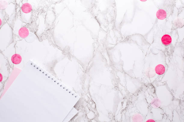 istock White notepad with pink decorations on a marble background in the office 1132994579