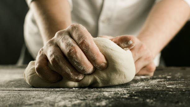 istock Male chef hands knead dough with flour on kitchen table 1132995035