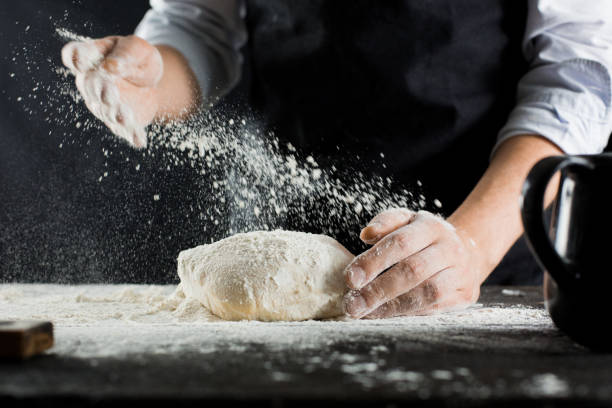 istock A chef in a black apron sprinkles flour on the kitchen table with flour 1132995090