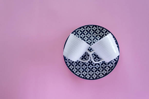 istock Overhead flat lay view of clean tableware (blue plate and two white coffee cups) on pink background 1132997424