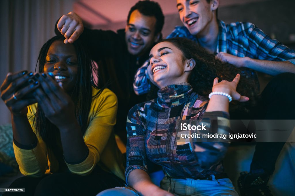 Group Of Friends Watching Funny Videos On Mobile Phone Stock Photo -  Download Image Now - iStock