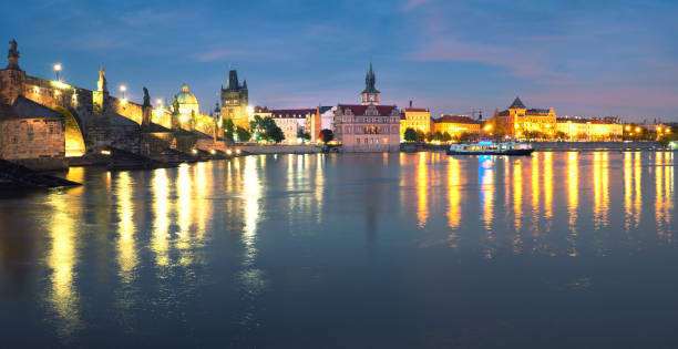 istock Panoramic image of illuminated Charles Bridge reflected in Vltava river at night 1132999997
