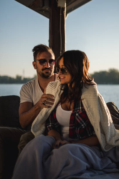 istock Man covering girlfriend with sweater by the river 1133001138
