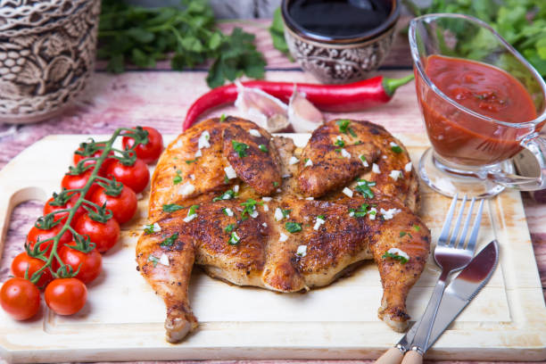 fried tapaka chicken (tobacco) on the board. traditional georgian and turkish dish. - кувшин imagens e fotografias de stock