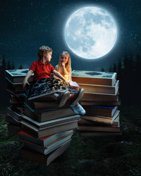 маленькая девочка и мальчик, сидящие на башне из больших книг - child ideas inspiration expertise стоковые фото и изображения