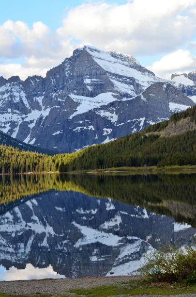 reflections of the snow covered mountains in glacier park, montana usa - lake us glacier national park cloudscape cloud imagens e fotografias de stock