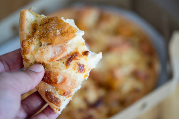 un uomo tiene un pezzo di pizza tra le mani. quell'uomo mangia una pizza. profondità di campo superficiale - human hand baked food pineapple foto e immagini stock