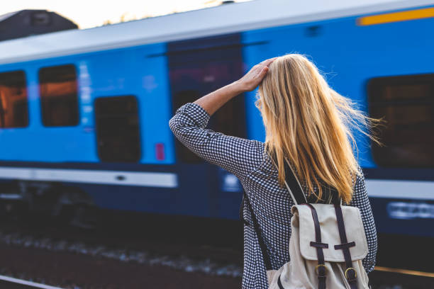 istock Woman with a backpack looking at a passing passenger train. 1133005759