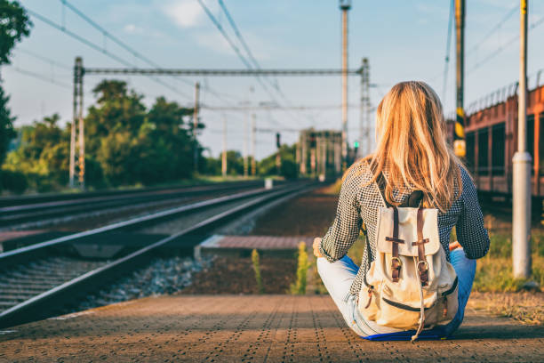 istock Backpacker woman sitting on railway station platform and waiting for train. 1133005946