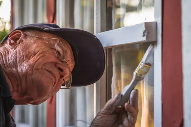 Senior man repairing house exterior.