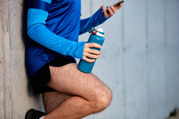 istock Close up of male runner leaning on wall and using smart phone. 1133010787