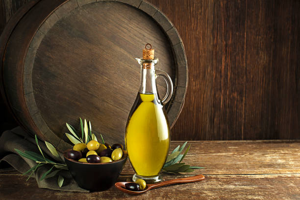 Bottle of Extra virgin healthy Olive oil Bottle of Extra virgin healthy Olive oil with barrel background olive oil pouring antioxidant liquid stock pictures, royalty-free photos & images