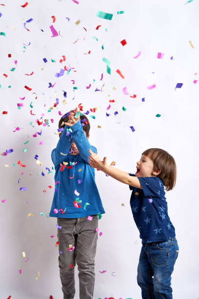 istock Children having fun with confetti in front of white background 1133014040