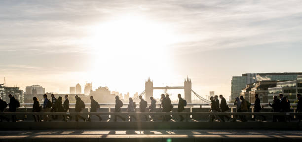 Morning rush hour across London Bridge at dawn. Bright sunlight and Tower Bridge in the background
