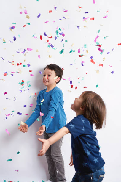 istock Children having fun with confetti in front of white background 1133014196