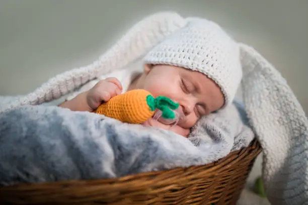 Photo of Newborn baby boy wearing bunny ears and tail in a basket.