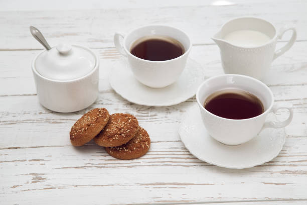 istock cups of tea with milk, cream and biscuits on wooden white table 1133019675