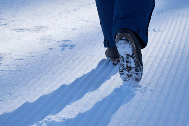 die beine des mädchens laufen im park im schnee mit streifen von der schneekatze. sonniger frost klarer wintertag. kopierraum - snow track human foot steps stock-fotos und bilder