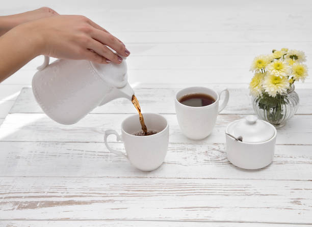 istock hands pours tea in cup of tea on wooden white table 1133021008