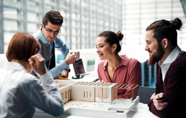 istock Group of young architects with model of a house working in office, talking. 1133024087
