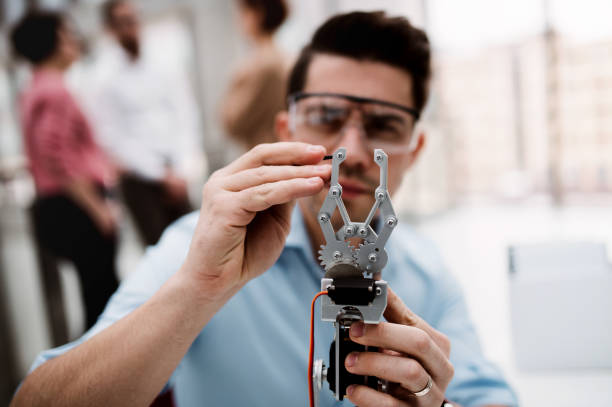 um homem de negócios ou um cientista novo com mão robótico que está no escritório, trabalhando. - inventor - fotografias e filmes do acervo