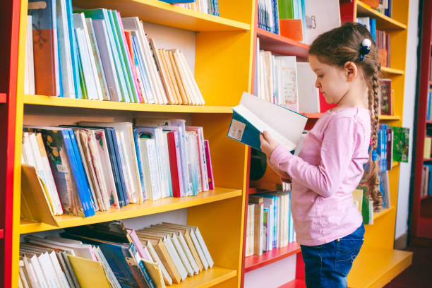 istock Little girl looking for a book in the library 1133027988