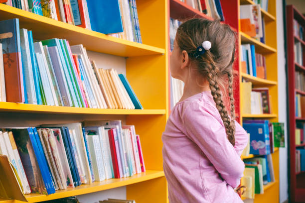 istock Little girl looking for a book in the library 1133027994