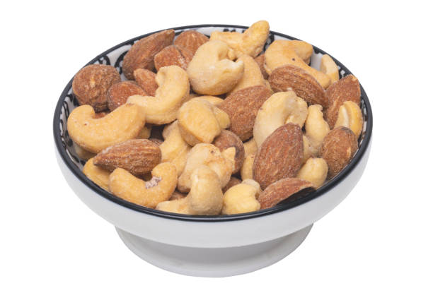 nüsse hintergrund. nahaufnahme von gerösteten und gesalzenen mandeln und cashewnüssen in einer keramikschüssel, die auf weißem hintergrund isoliert ist. gourmet-nuss mix mit mandeln. makro. - beer nuts food isolated white stock-fotos und bilder