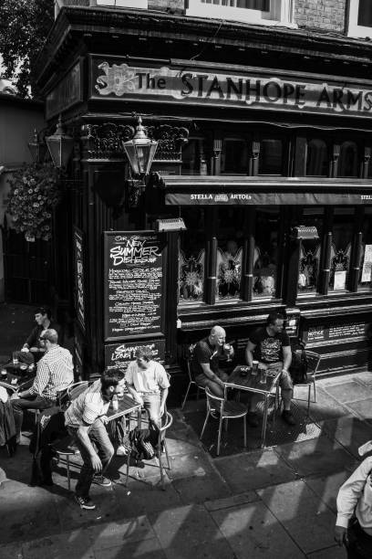 les gens boivent de la bière aux tables de streetside du stanhope arms pub à londres, royaume-uni - london store photos et images de collection