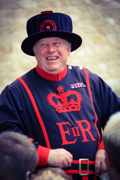 A Yeomen Warder, or better known as Beafeater, in front of the Queen's House at Her Majesty's Royal Palace and Fortress of the Tower of London, United Kingdom A member of the "Yeomen Warders of Her Majesty's Royal Palace and Fortress the Tower of London and Member of the Sovereign's Body Guard of the Yeoman Guard Extraordinary" explaining the Tower of London to tourists and laughing. United Kingdom. September 4th 2011. queen's house stock pictures, royalty-free photos & images