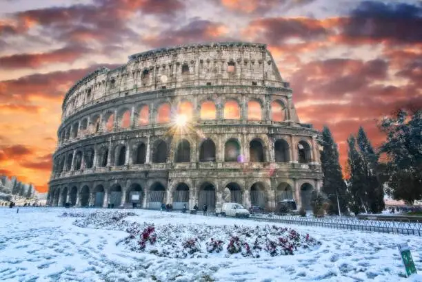 Ancient Rome Colosseo after snow with raylights coming from one of the Windows in the center.