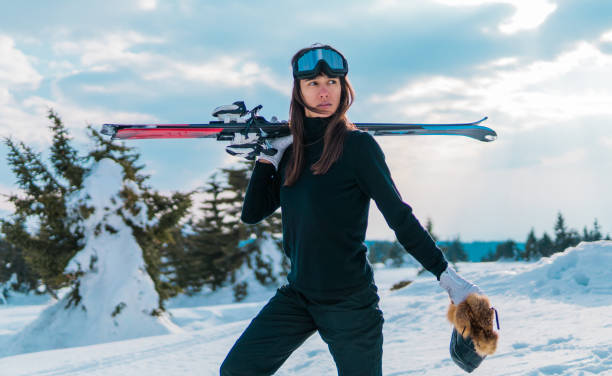 Woman walking in mountains holding ski stock photo