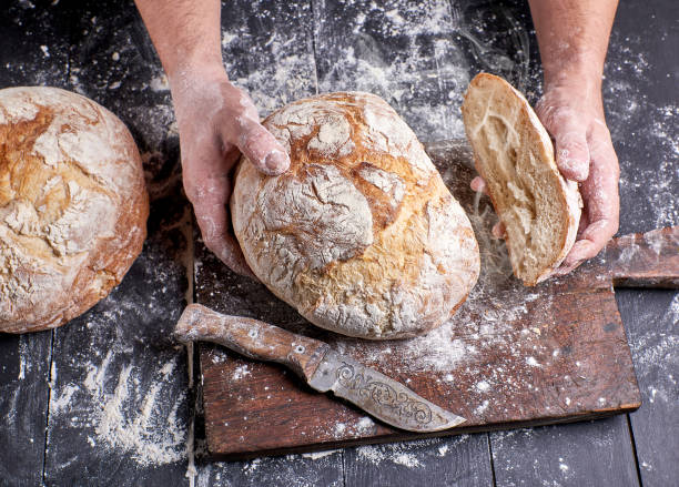 istock chef in a black uniform holding fresh hot baked round bread 1133038561