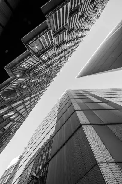 Highly detailed abstract wide angle view up towards the sky in the financial district of London City and its ultra modern contemporary buildings and conceptual architecture. Image is ideal for background. Shot on Canon EOS R full frame system. Monochrome edit in Black and White image with high contrast.