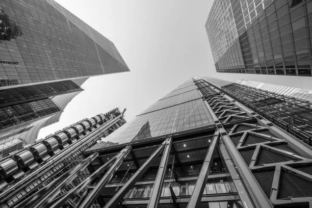 Highly detailed abstract wide angle view up towards the sky in the financial district of London City and its ultra modern contemporary buildings. Shot on Canon EOS R full frame.  Monochrome edit in Black and White image with high contrast.
