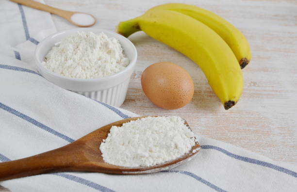 Ingredients for Banana Pancakes Preparation Baking Accessories Kitchen Composition Wooden Table Top Metal Whisk Wooden Spoon Bananas Eggs Milk