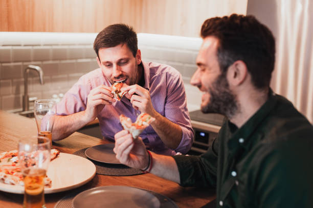 istock Two guys enjoying eating pizza at home 1133044350