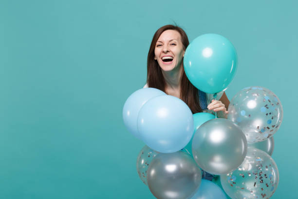 porträtt av glada skratt söt ung kvinna i denim kläder firar och hålla färgglada luft ballonger isolerade på blå turkos vägg bakgrund. födelsedag semester fest, människor känslor koncept. - kvinna ballonger bildbanksfoton och bilder