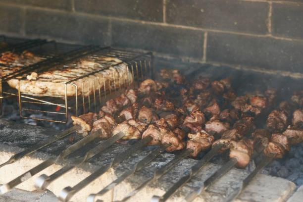 Roasted meat cooked at barbecue. Grilled kebab cooking on metal skewer. BBQ fresh beef meat chop slices. Traditional eastern dish, shish kebab. Grill on charcoal and flame, picnic, street food