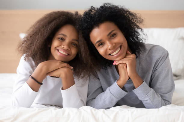 istock African older younger sisters lying on bed posing for camera 1133045004