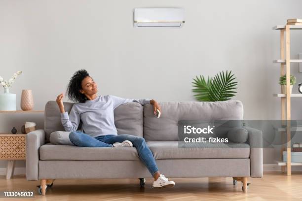 African Young Relaxed Woman Sitting On Couch Breathing Fresh Air Stock Photo - Download Image Now
