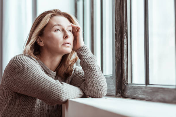 istock Beautiful mature woman feeling stressed looking into window 1133047595