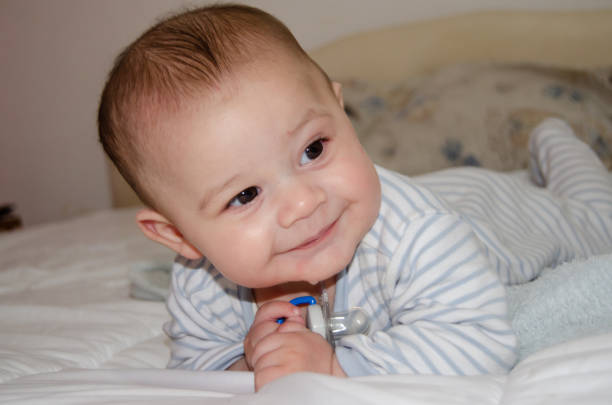 cute 4 months old baby boy having tummy time and making funny faces - early development concept