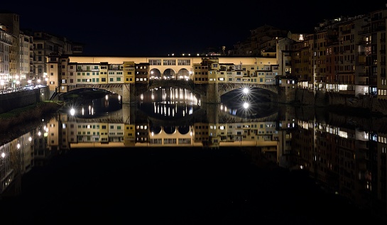 Florence, Italy - February 26, 2019. Ponte Vecchio photographed at night. The reflection of the bridge. the reflection of the palaces the anointed the arno.