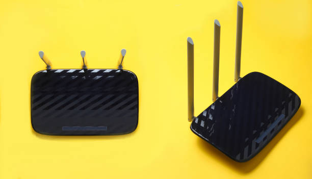 istock Black Three-antenna wi-fi router isolated on yellow background. Set of two different foreshortenings 1133054902